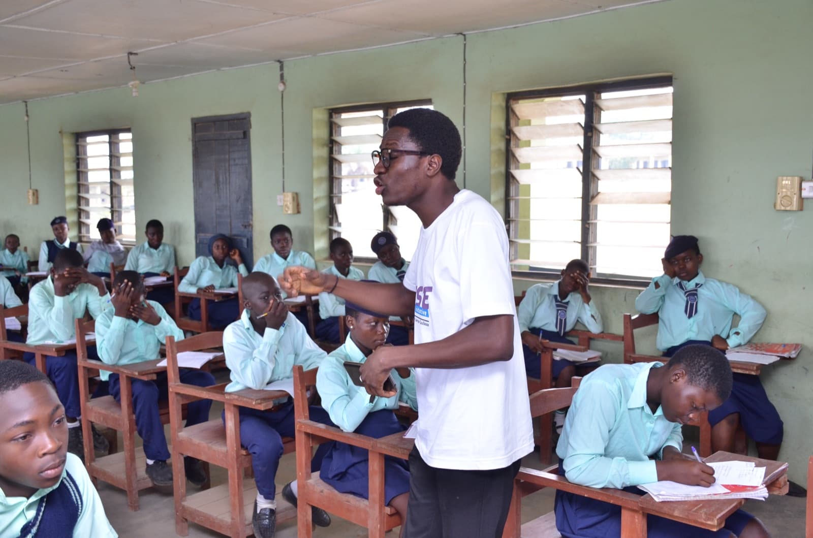 A facilitator standing among seated students at the 2019 bootcamp, Aatan Baptist Comprehensive High School.