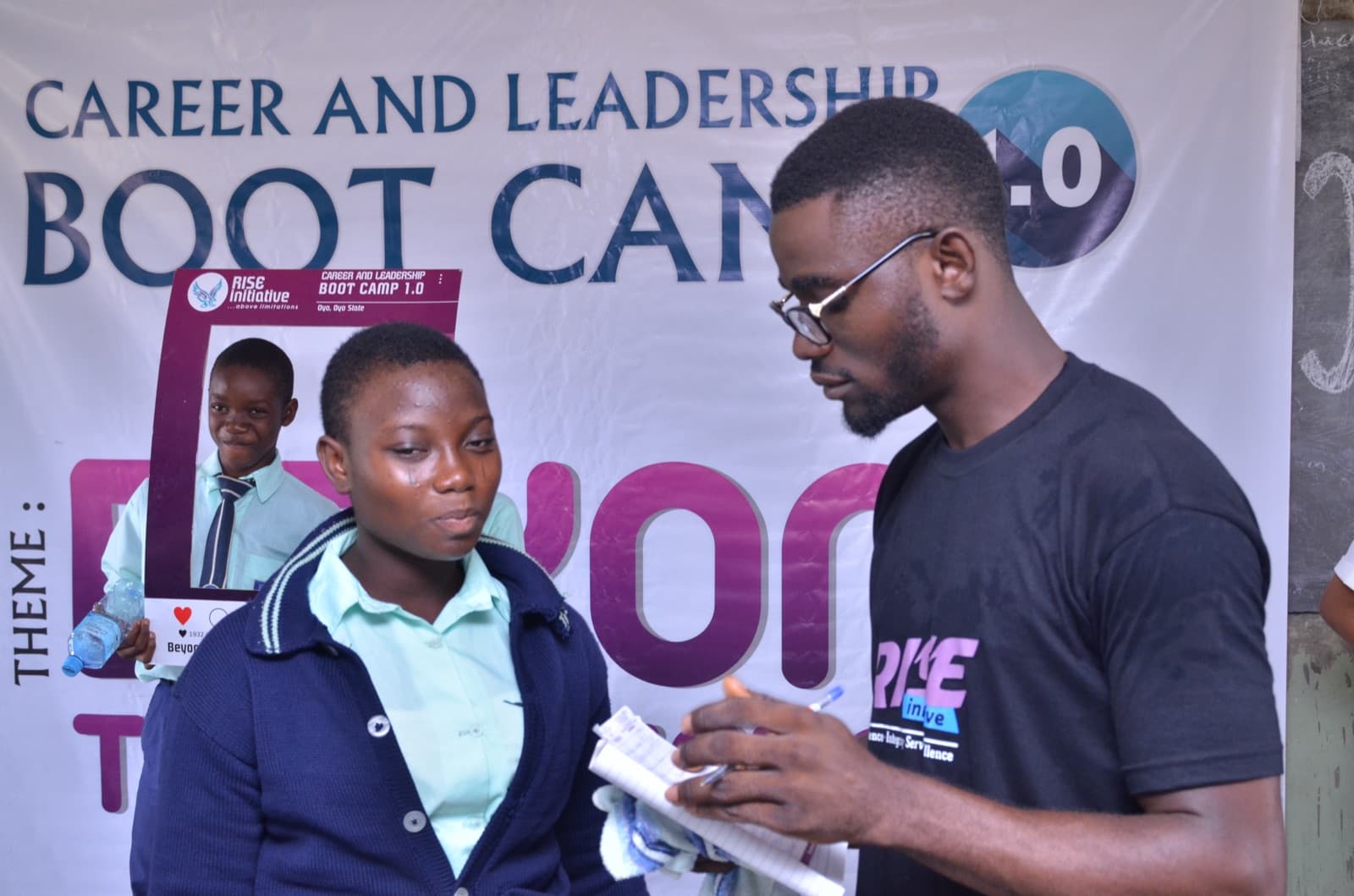 A facilitator speaking with a student at the front of the hall, Aatan Baptist Comprehensive High School, 2019.