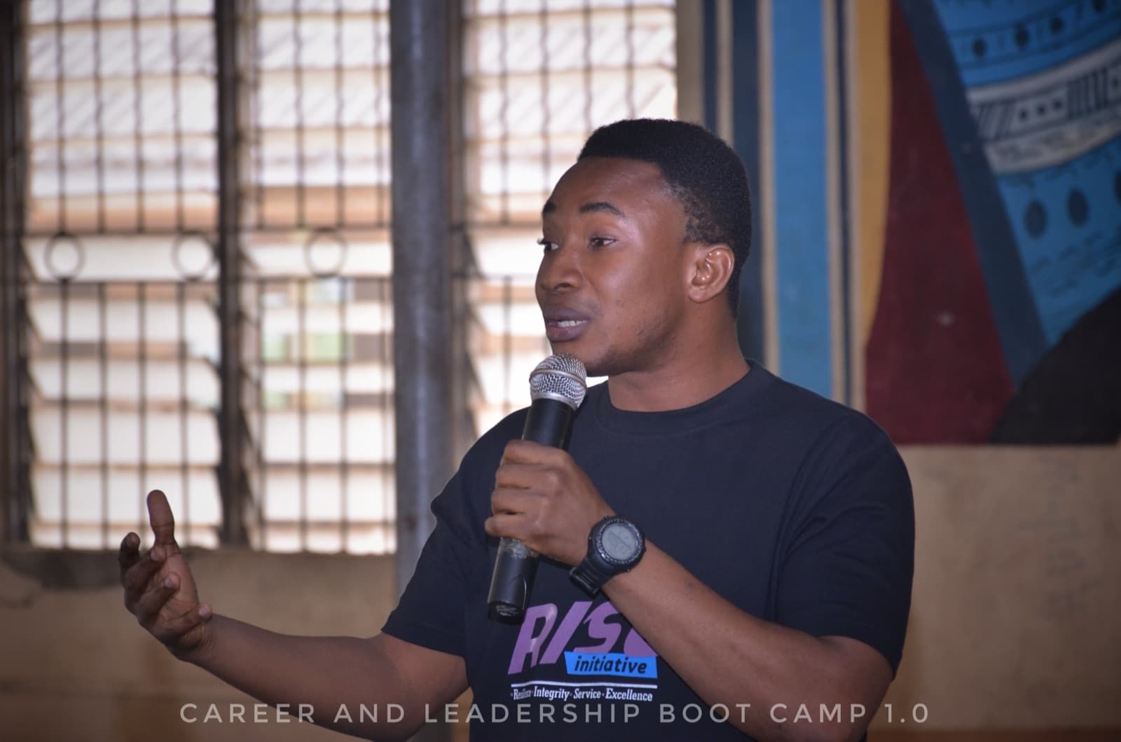 A RISE Initiative facilitator speaking into a microphone at a community session.
